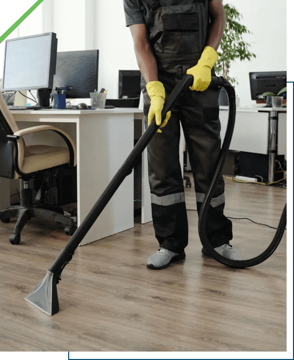 Person vacuuming a wooden office floor with a carpet cleaner.